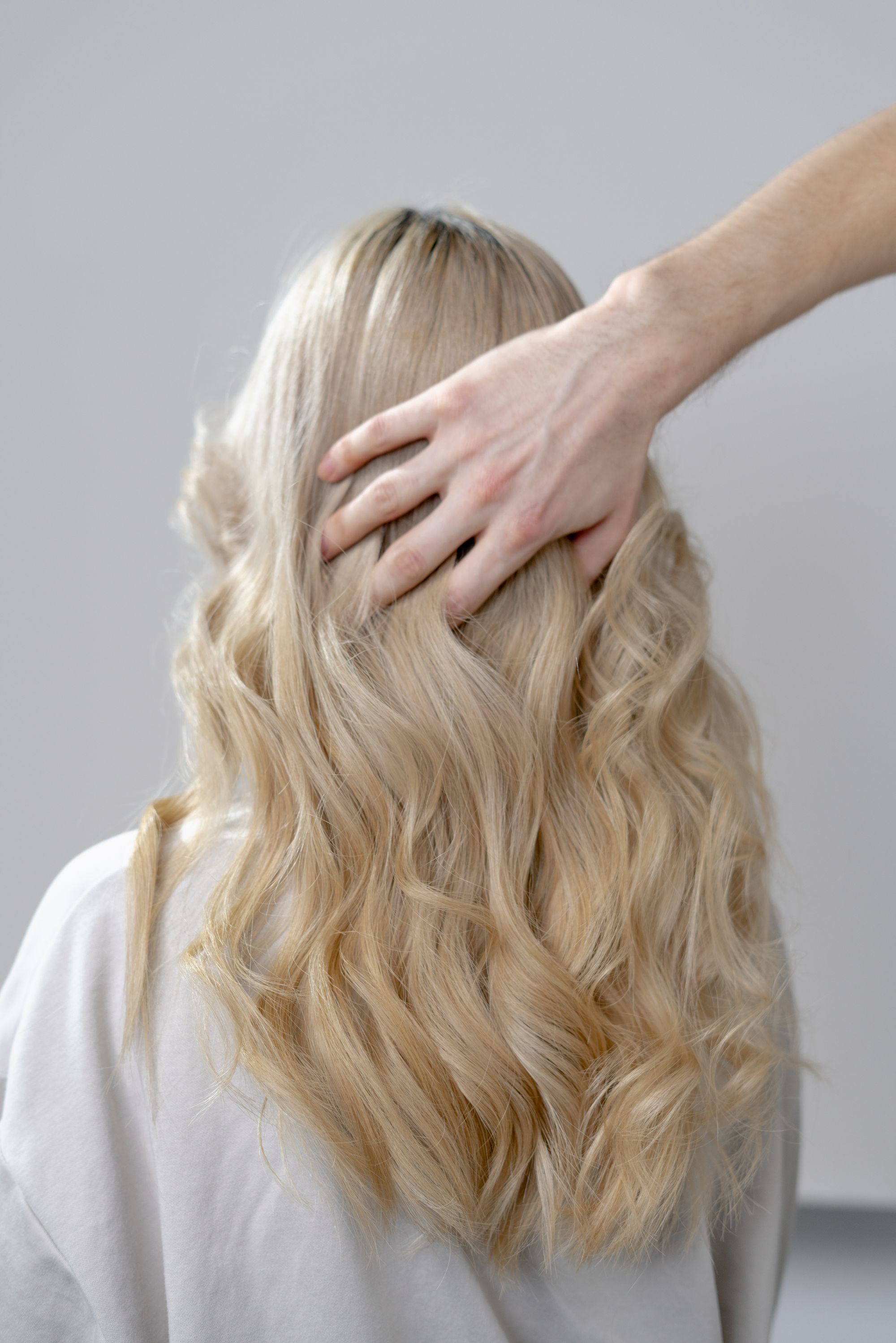 Creamy blonde waves with a hand resting in the hair