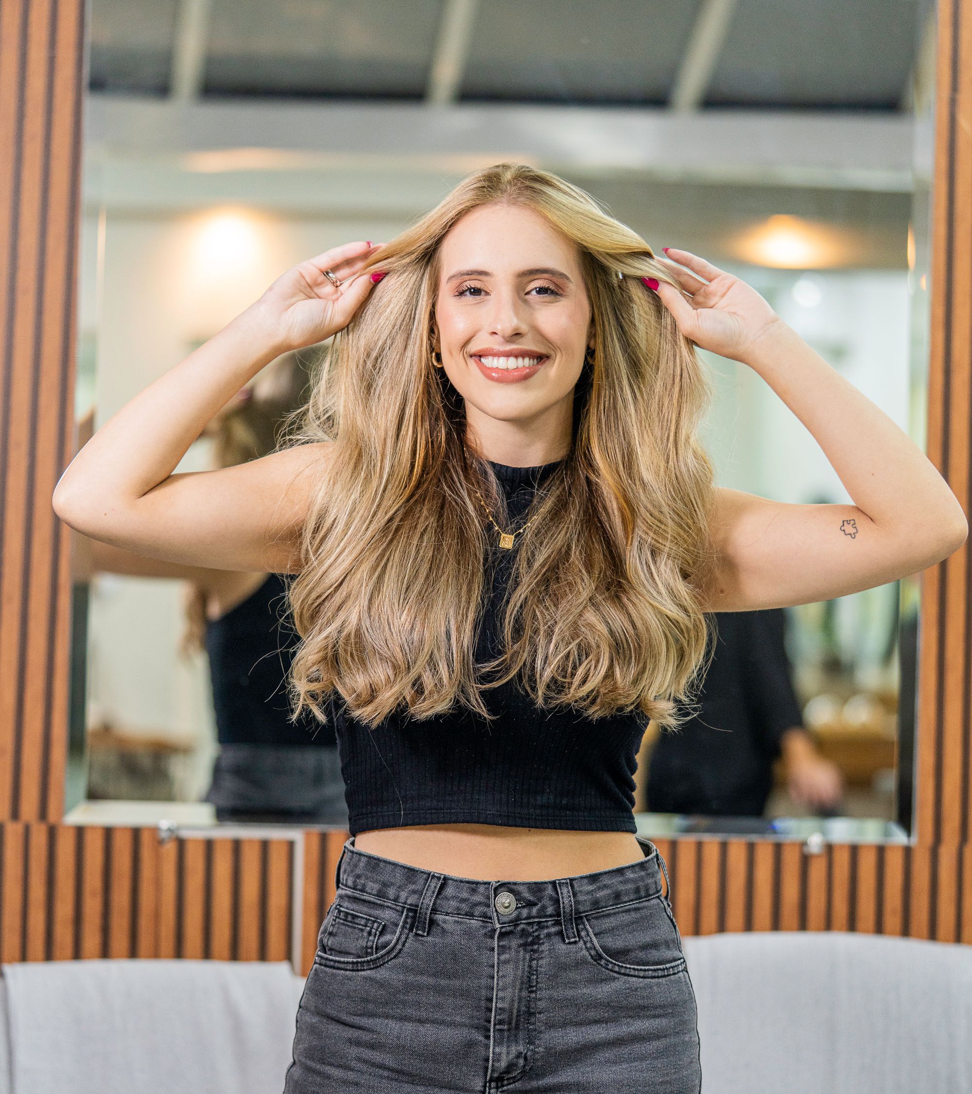 A client laughing with her hands in freshly finished blonde waves